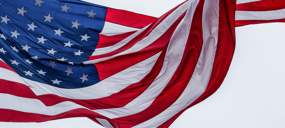 USA flag waving in the wind, with red, white, and blue stripes and stars 