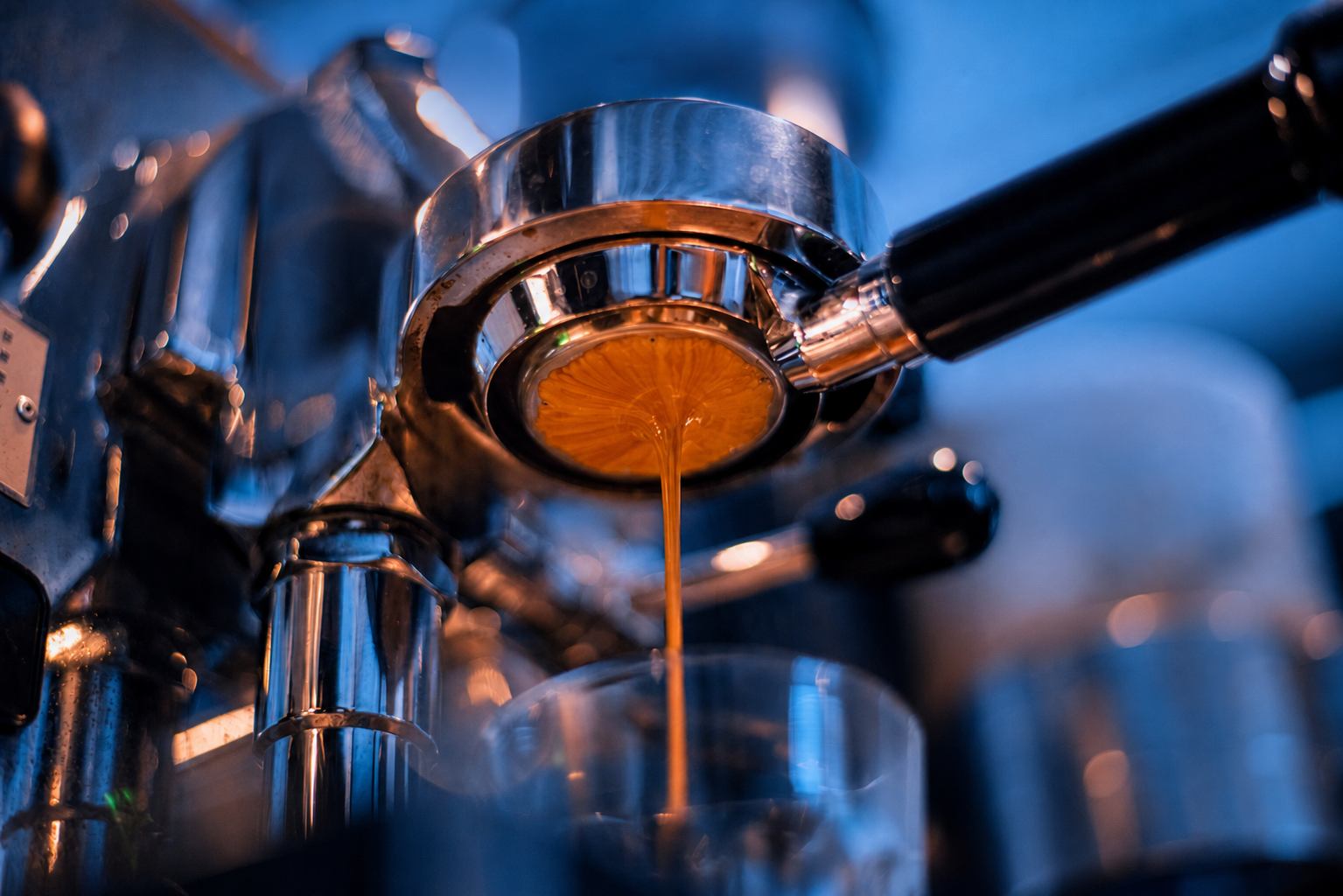 Espresso flowing from a commercial coffee machine into a white cup